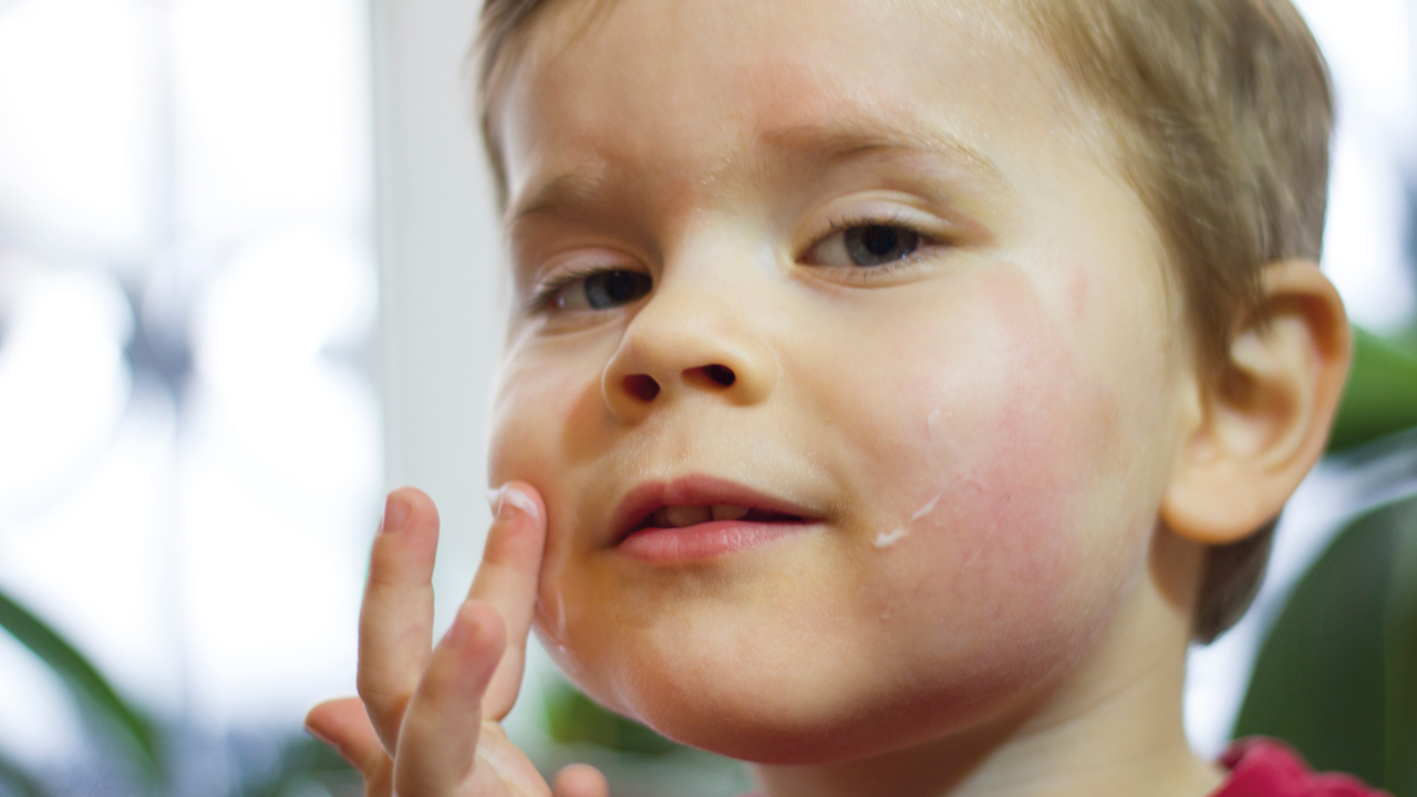 young child putting cream on cheek.jpg